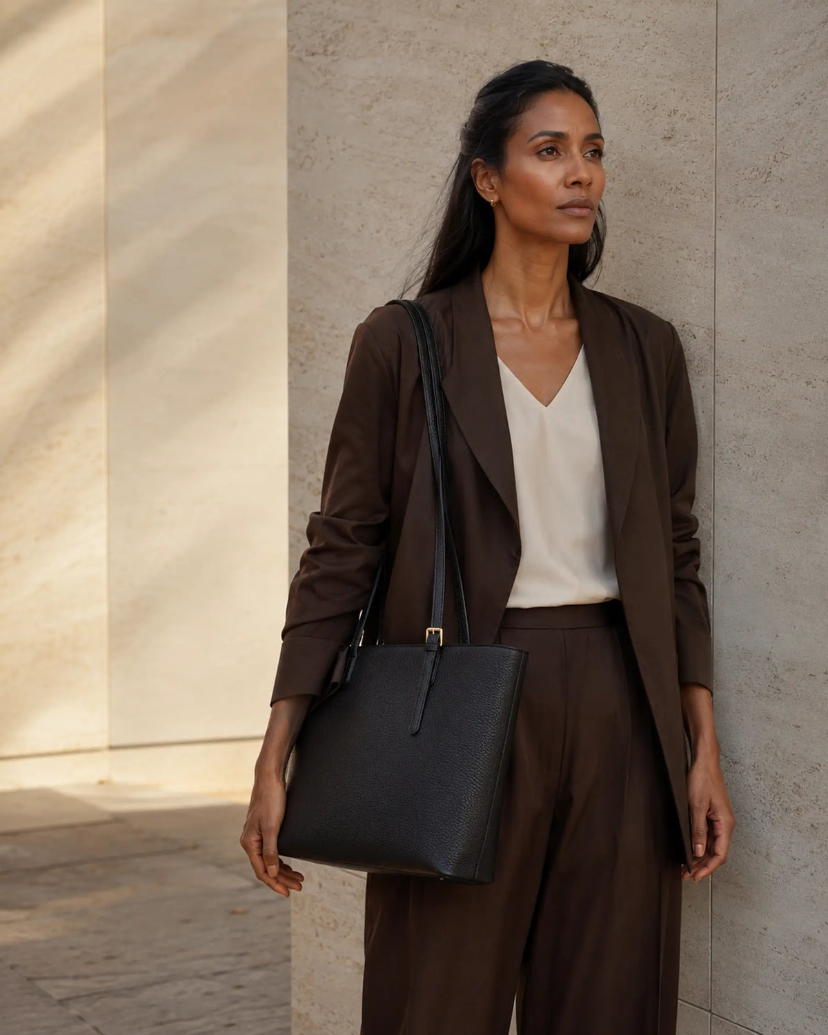 Mulher com bolsa preta Femily em ambiente de pedra escura